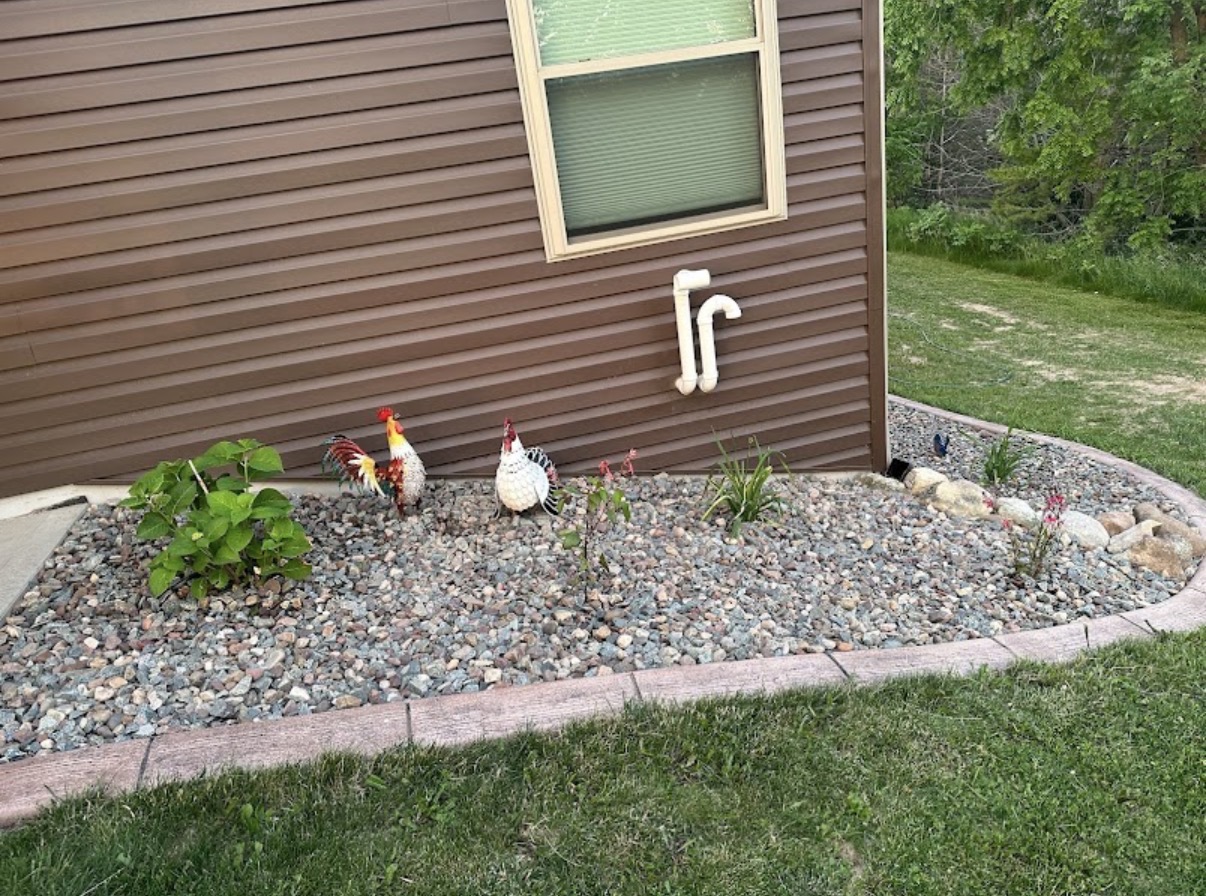 Freshly edged rock flower bed with new plants and brick border